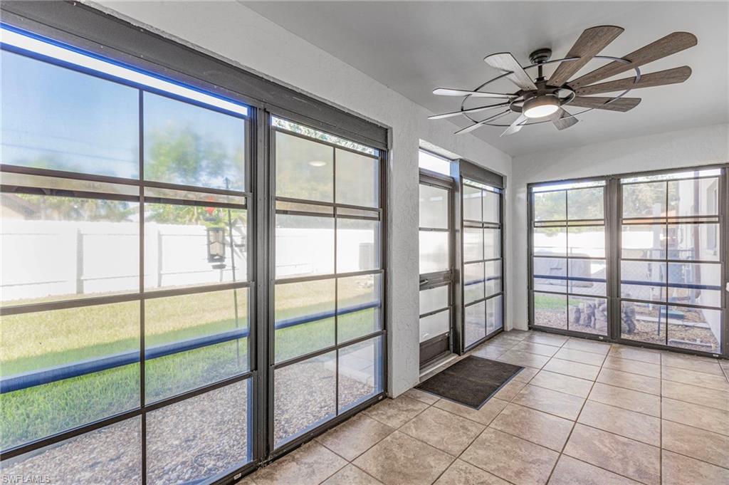 Unfurnished sunroom with ceiling fan and tile patterned floors