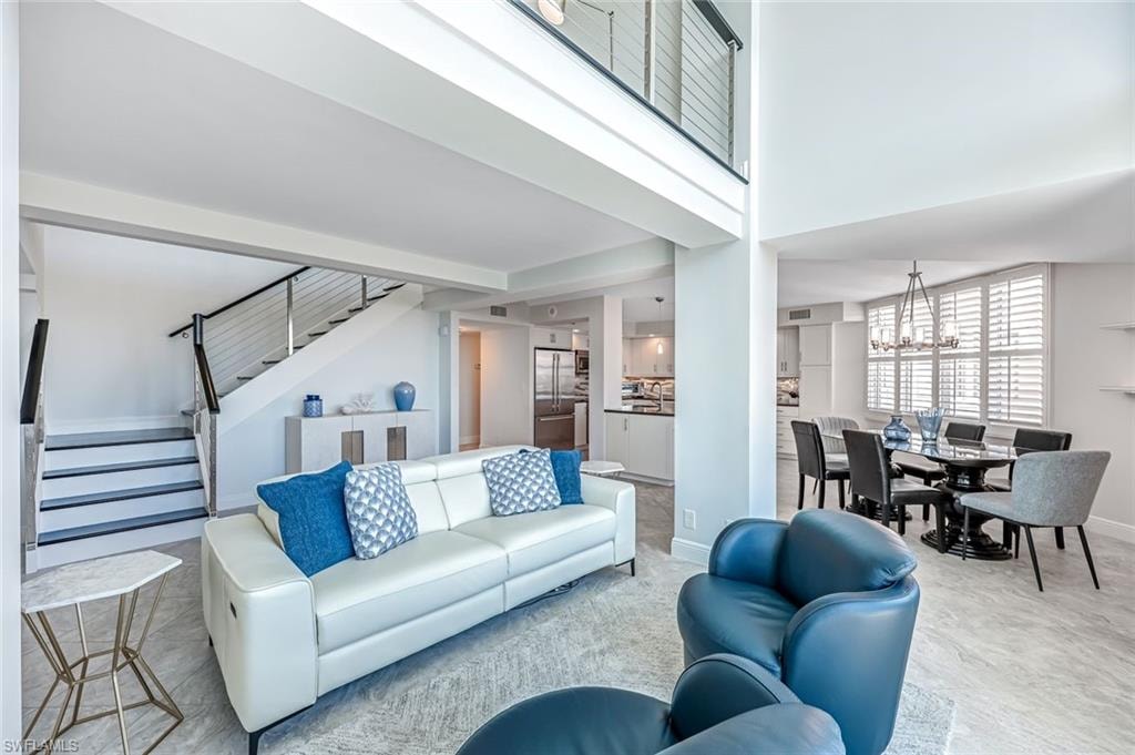 Living room with stairs, a towering ceiling, and a chandelier