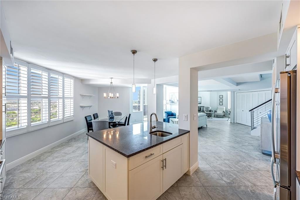 Kitchen with open floor plan, freestanding refrigerator, dark stone countertops, and hanging light fixtures