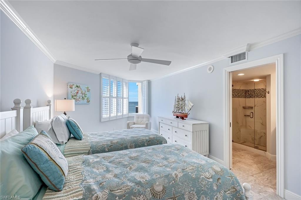 Bedroom featuring crown molding, a ceiling fan, light tile patterned floors, and ensuite bath