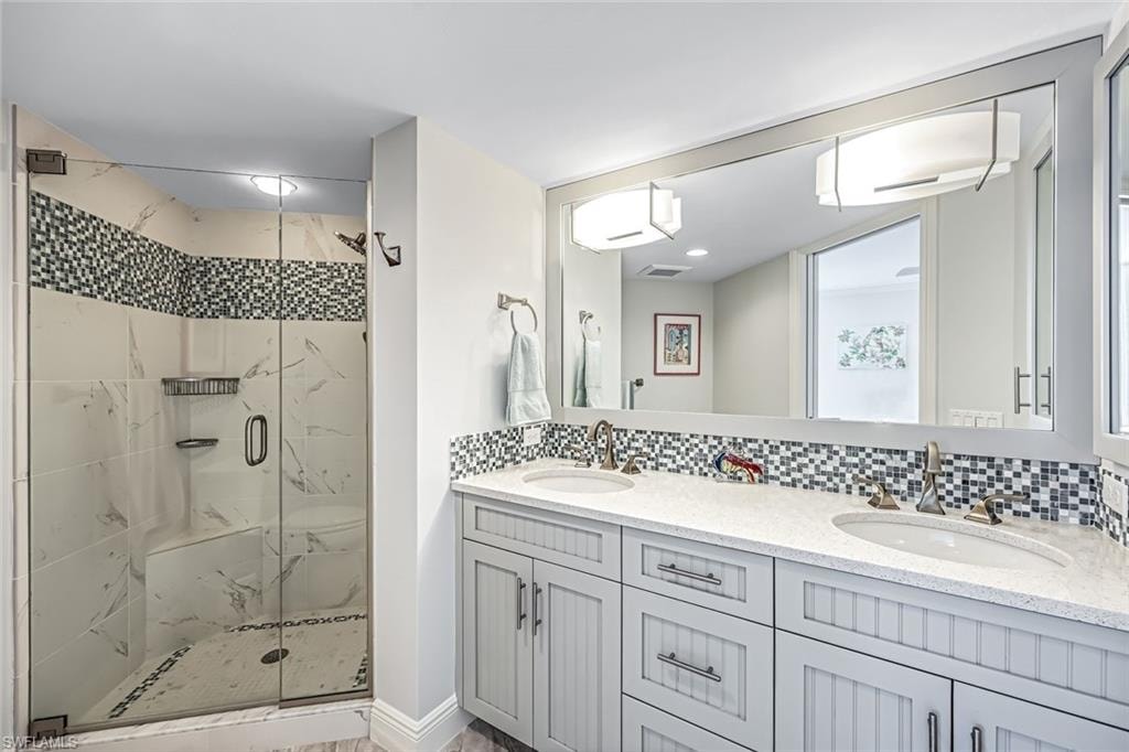 Bathroom with decorative backsplash, a marble finish shower, double vanity, and a wall unit AC