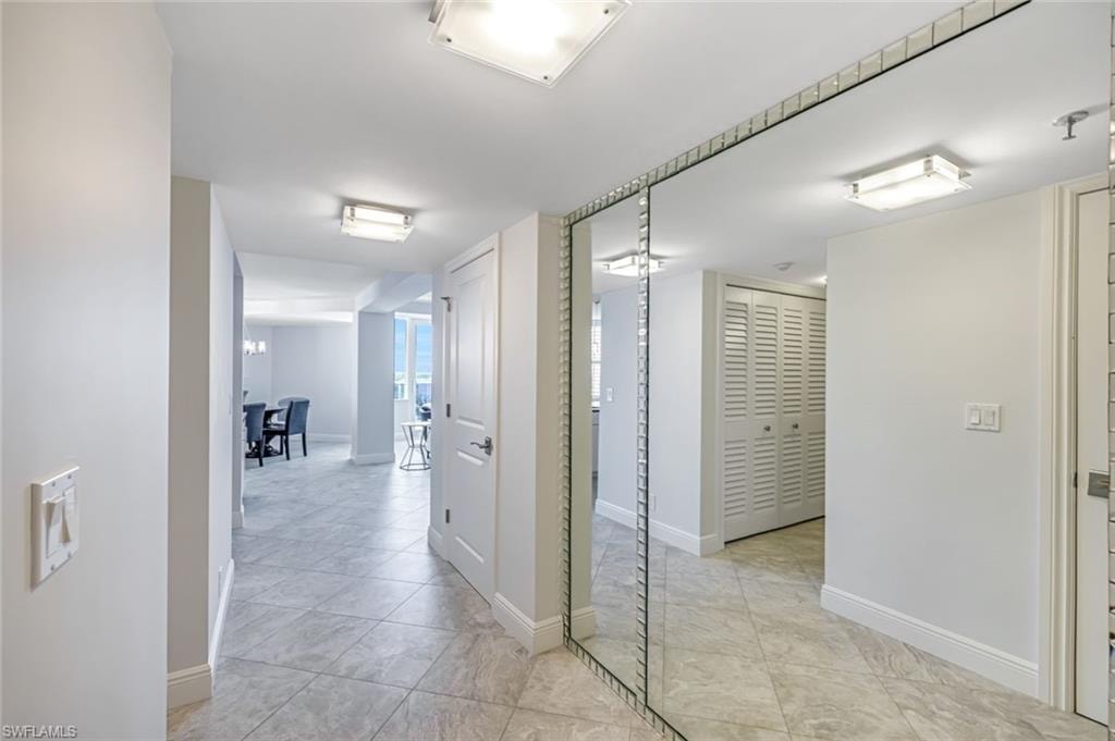 Hall with baseboards and light tile patterned floors