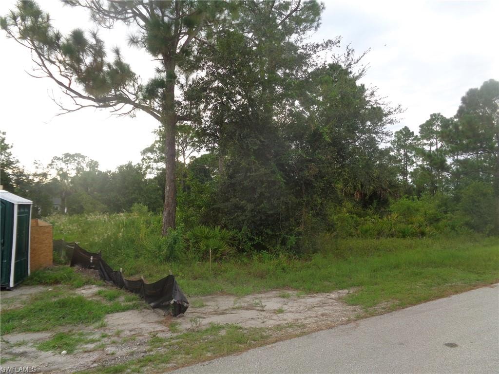 View of asphalt street featuring view of wooded area