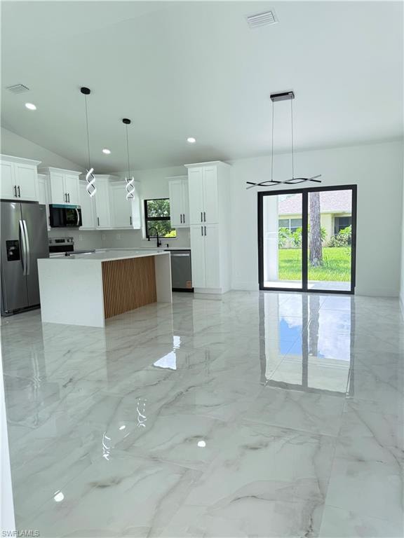Kitchen featuring pendant lighting, light marble finish flooring, stainless steel appliances, white cabinetry, and recessed lighting