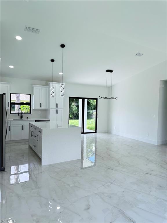 Kitchen with light marble finish floors, hanging light fixtures, plenty of natural light, and recessed lighting