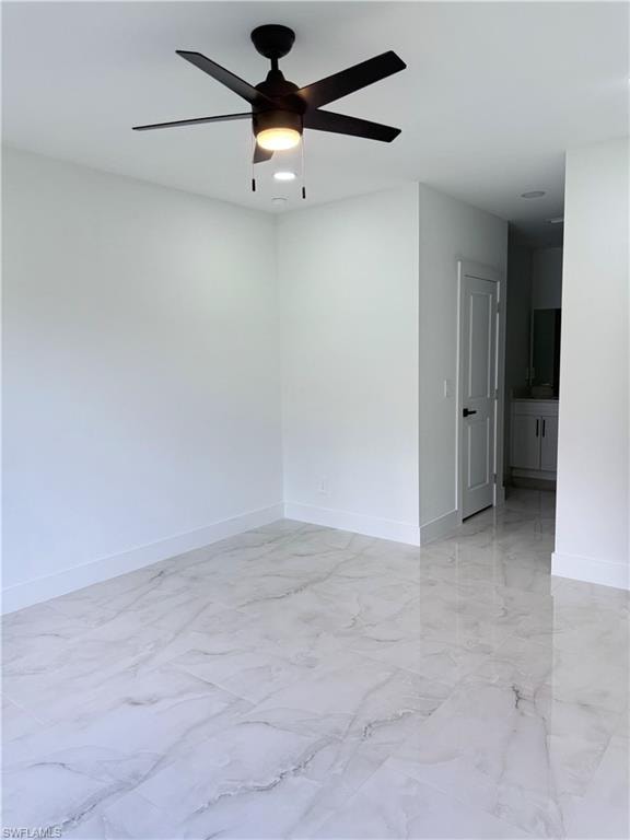 Empty room featuring light marble finish flooring and ceiling fan