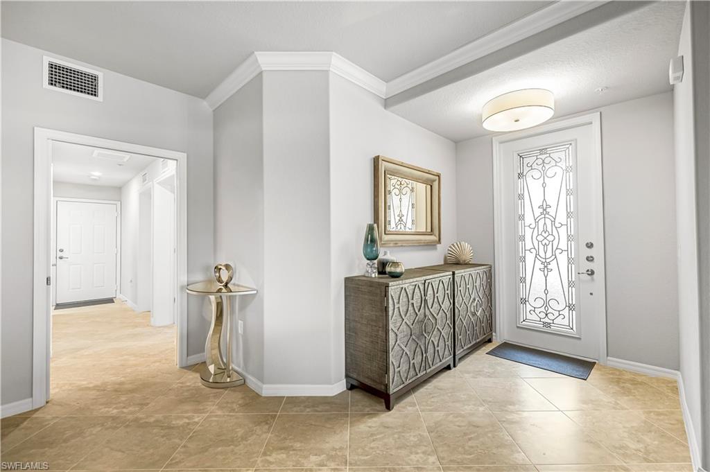 Entryway with light tile patterned floors and crown molding