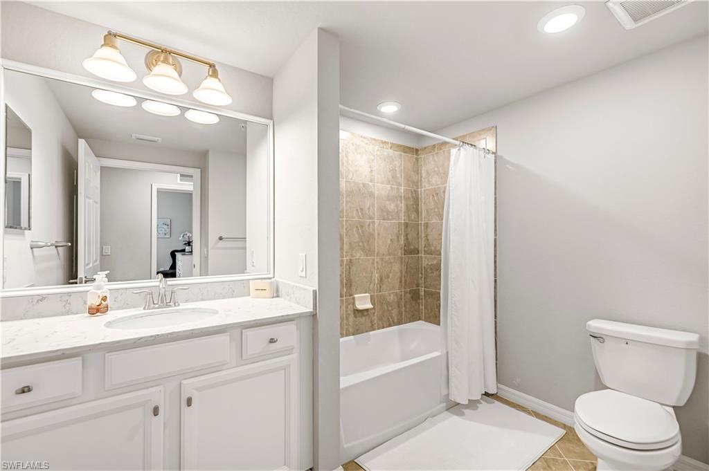 Full bath featuring light tile patterned floors, vanity, shower / bath combo with shower curtain, and recessed lighting