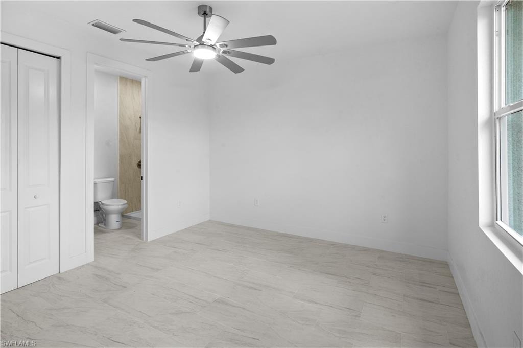 Unfurnished bedroom featuring a ceiling fan, multiple windows, and a closet