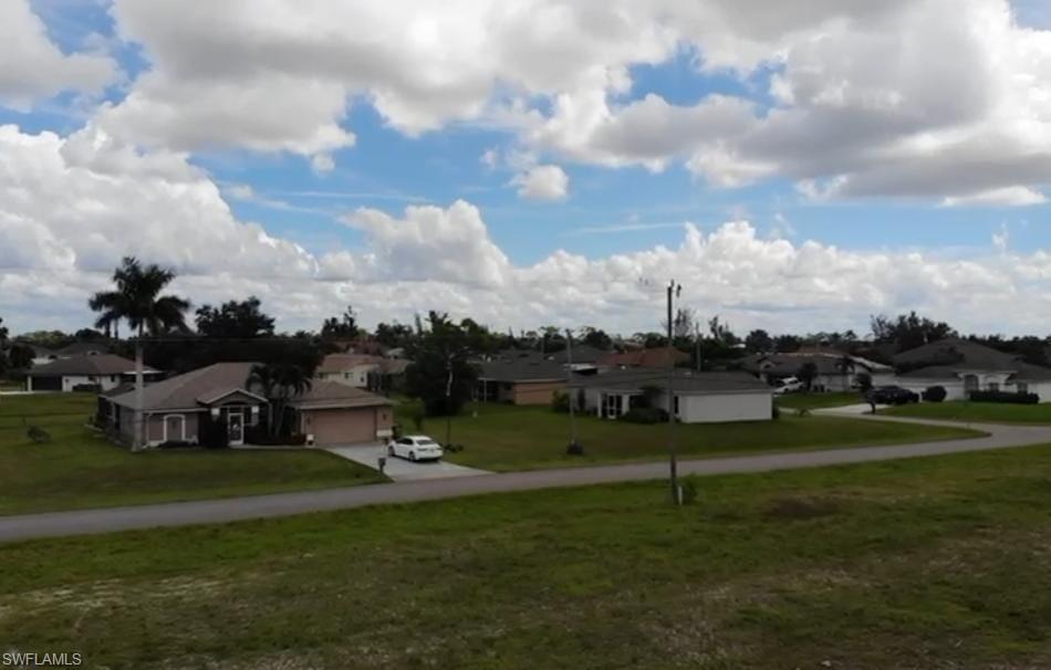View of grassy yard with a residential view, driveway, and a garage