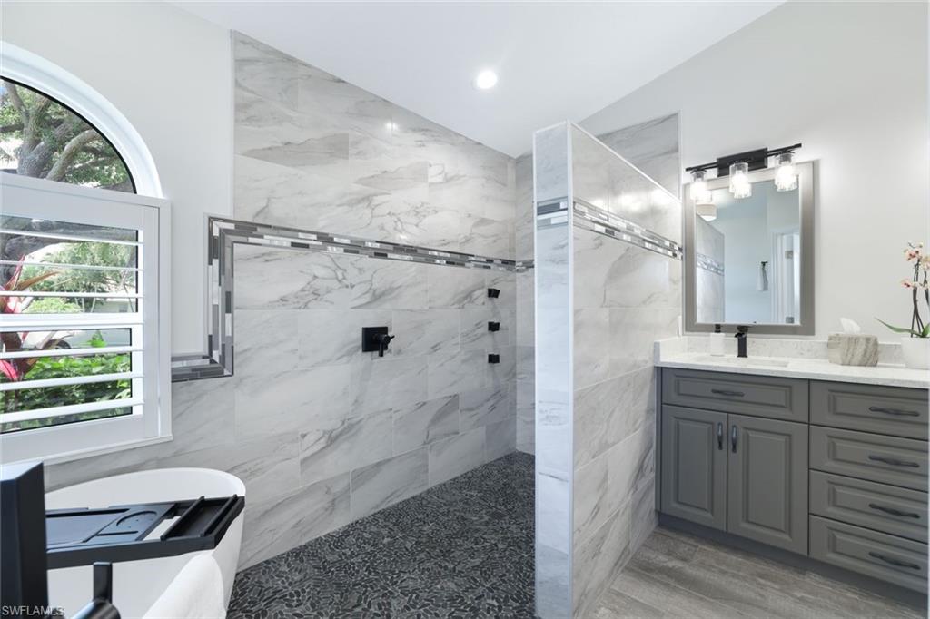 Bathroom with vanity, tiled shower, hardwood / wood-style floors, and tile walls