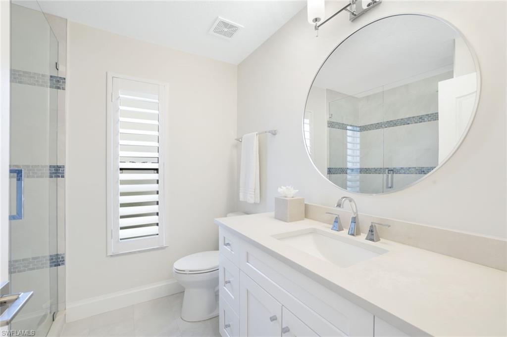 Bathroom featuring vanity, toilet, tile patterned flooring, and an enclosed shower