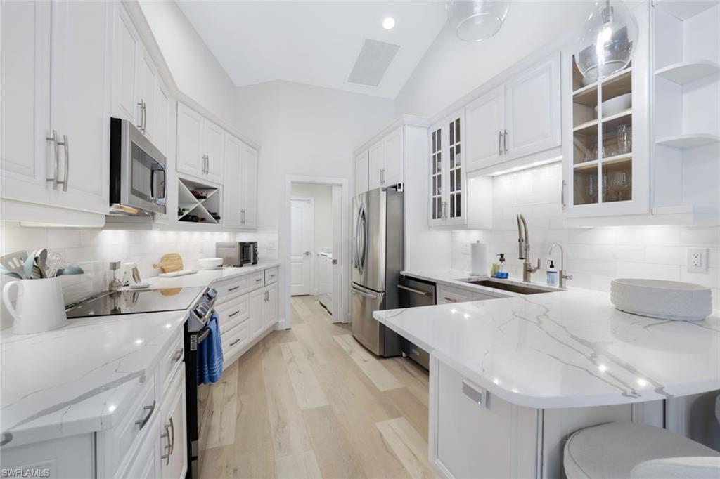 Kitchen featuring white cabinetry, light hardwood / wood-style flooring, backsplash, appliances with stainless steel finishes, and sink