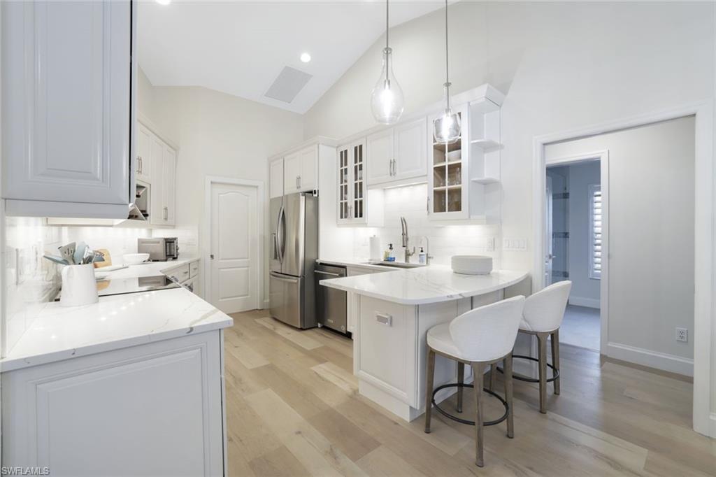 Kitchen featuring appliances with stainless steel finishes, tasteful backsplash, kitchen peninsula, and light wood-type flooring