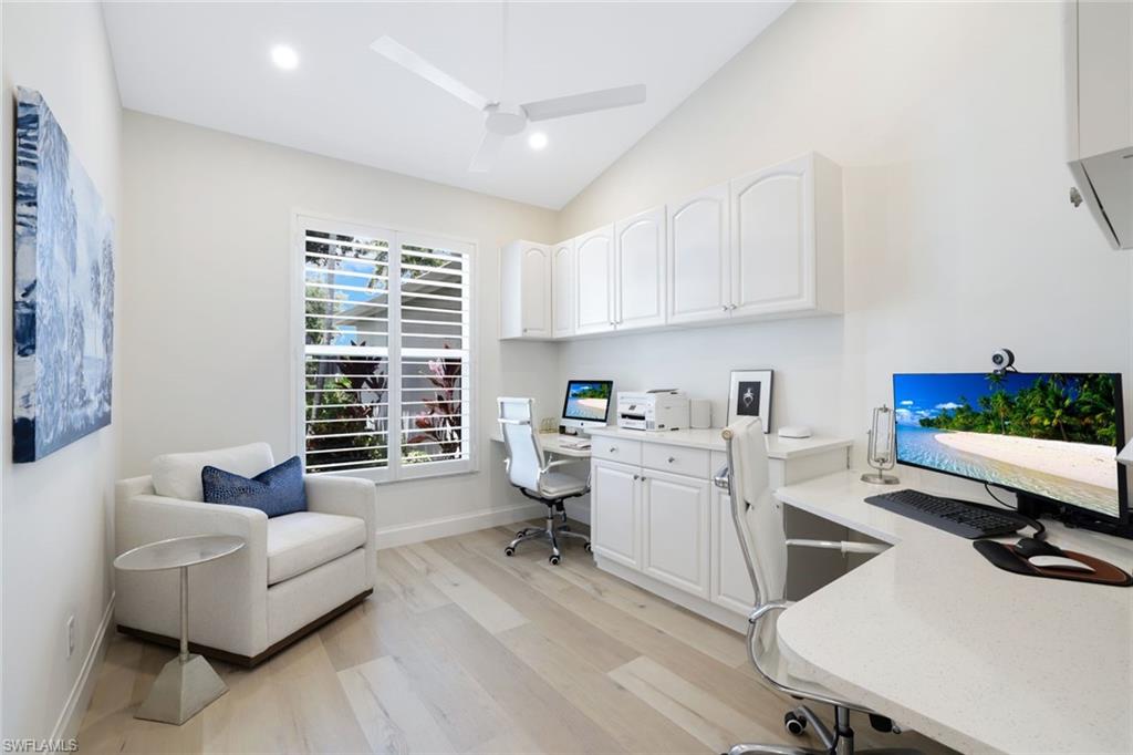 Home office with light hardwood / wood-style floors, vaulted ceiling, and ceiling fan