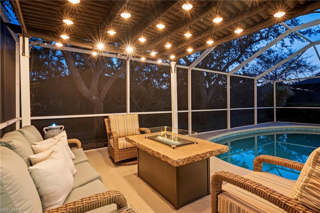 View of pool featuring an outdoor living space with a fire pit, glass enclosure, and a patio area