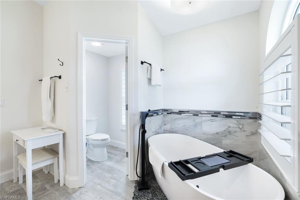 Bathroom with toilet, hardwood / wood-style flooring, and a bath