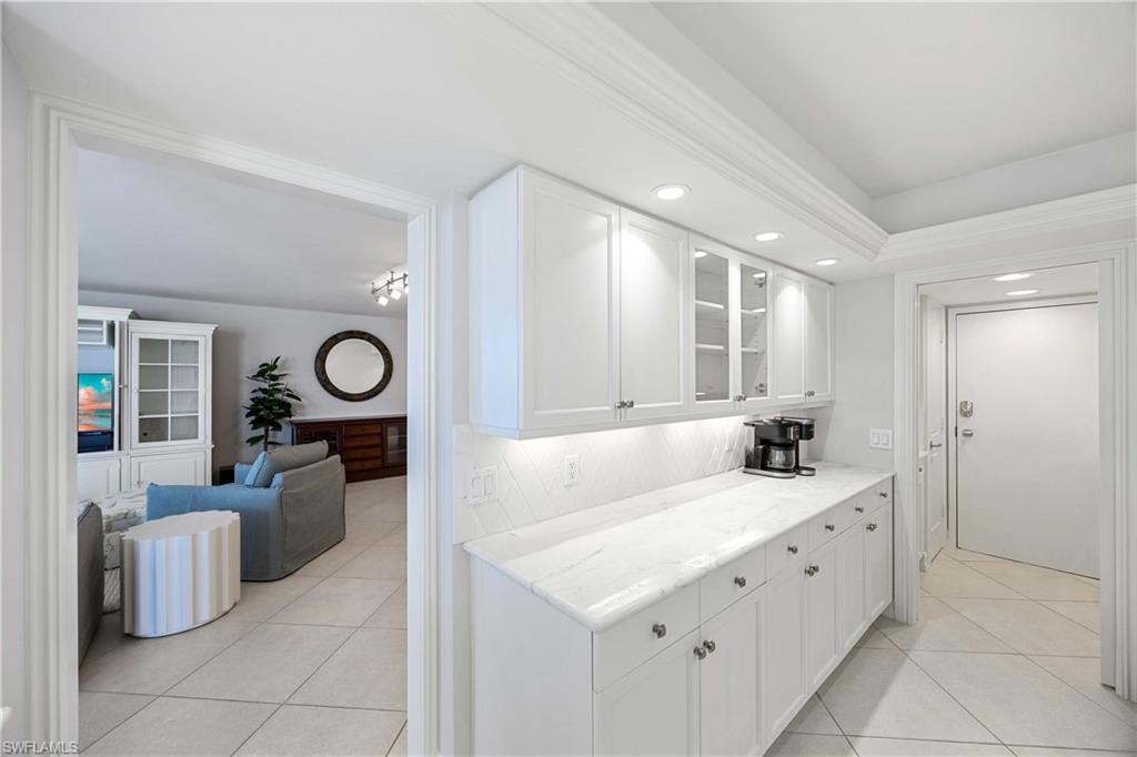 Kitchen with glass insert cabinets, light tile patterned floors, white cabinetry, light stone countertops, and recessed lighting