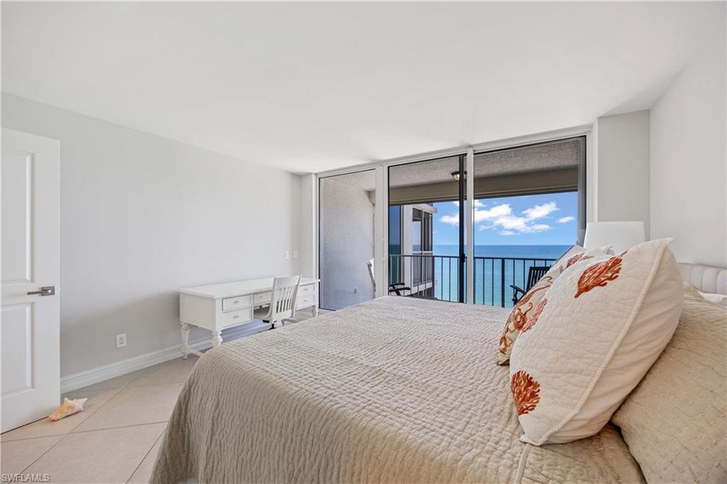 Bedroom featuring expansive windows, light tile patterned floors, a water view, and access to outside