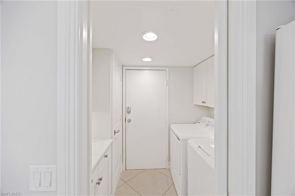 Washroom featuring light tile patterned flooring, cabinet space, washer and clothes dryer, and recessed lighting