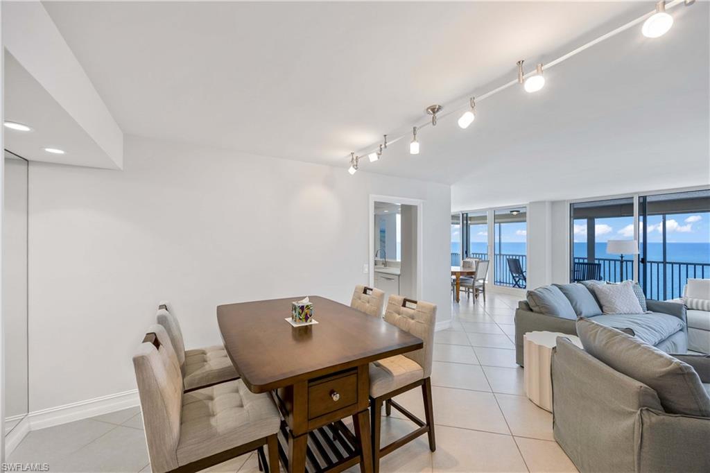 Dining room featuring light tile patterned floors, a water view, floor to ceiling windows, and track lighting