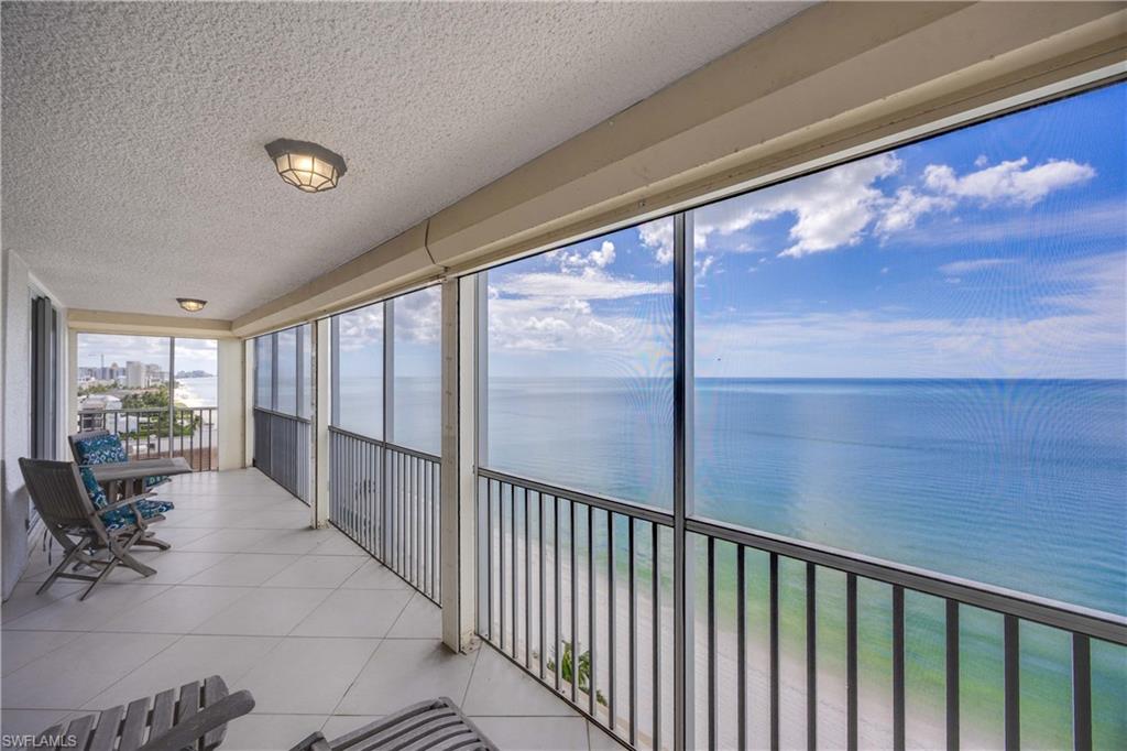 Sunroom featuring a balcony, a textured ceiling, a water view, and tile patterned floors