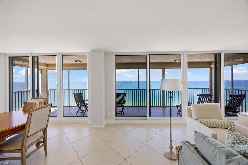 Living area with tile patterned flooring, a water view, plenty of natural light, and floor to ceiling windows