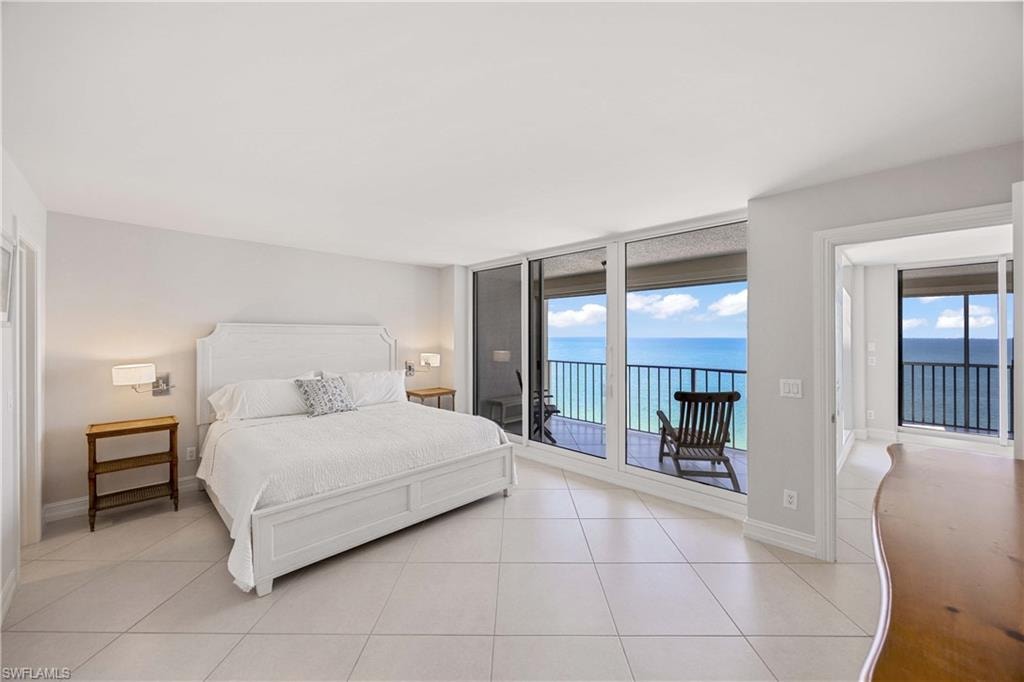 Bedroom with access to outside, a water view, expansive windows, and light tile patterned floors
