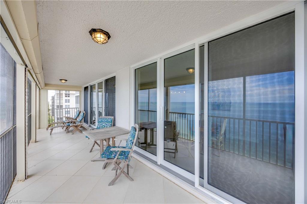 Sunroom / solarium with expansive windows, a textured ceiling, tile patterned flooring, a water view, and a balcony