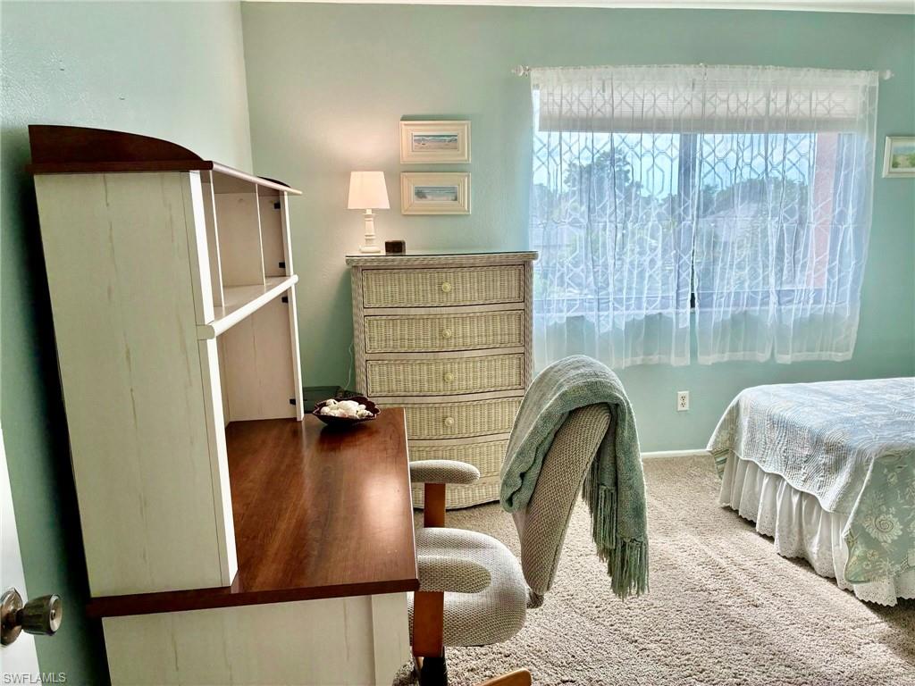 Bedroom with multiple windows, an office area, and carpet flooring