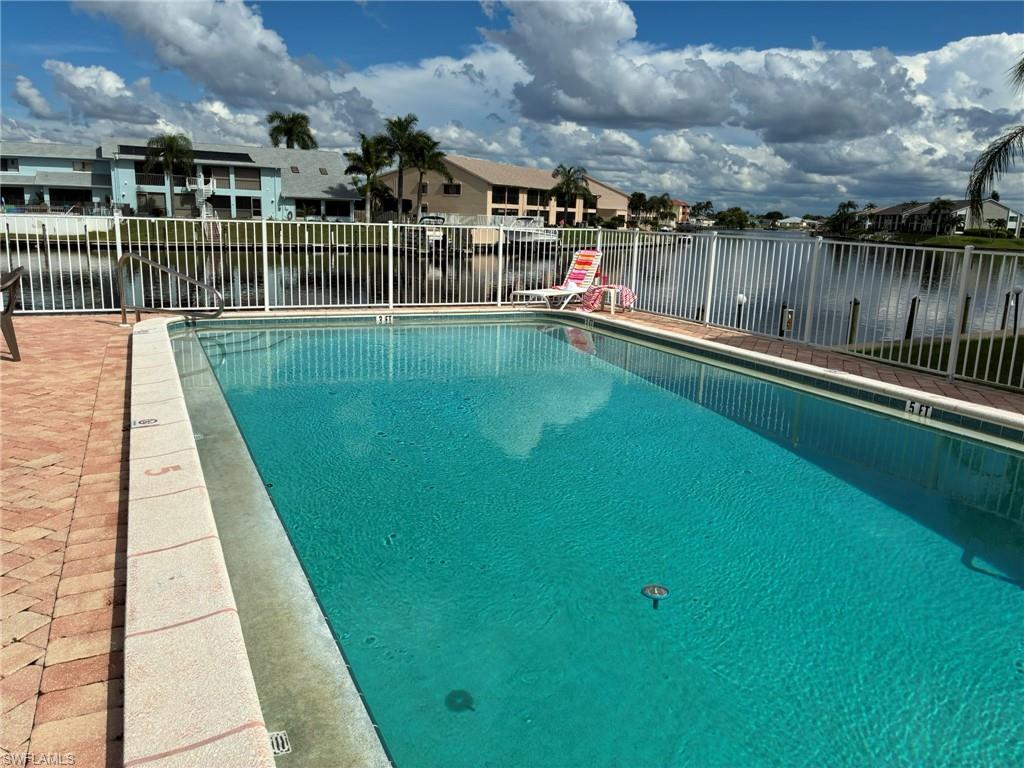 Community pool featuring a water view, a residential view, and a patio area
