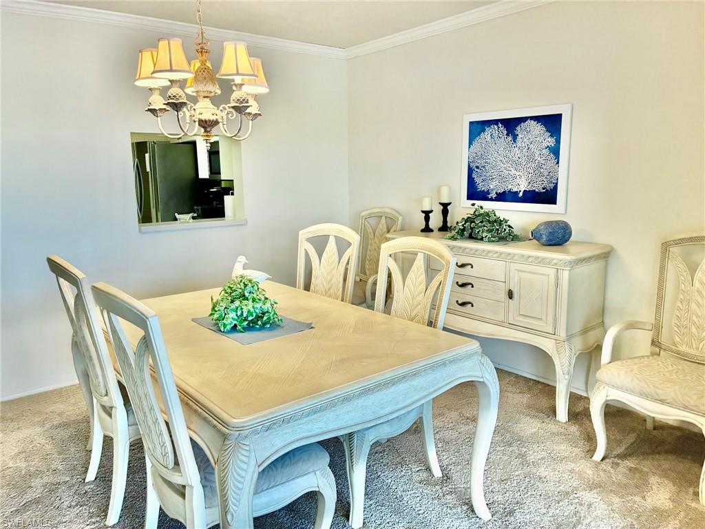 Carpeted dining room featuring ornamental molding and a chandelier