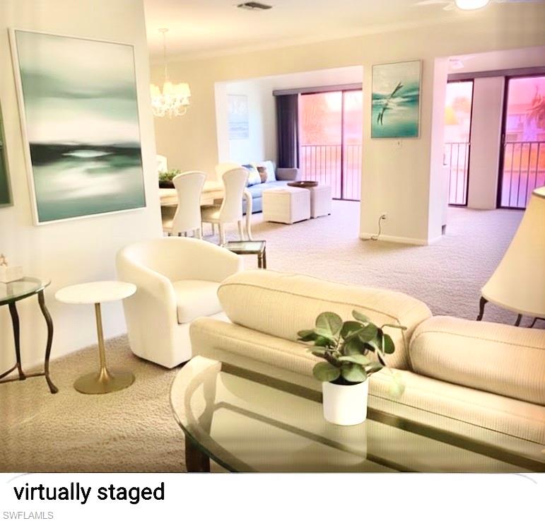 Living area with carpet flooring, a chandelier, and crown molding
