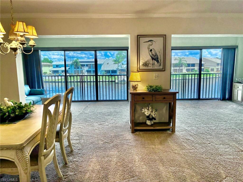 Carpeted dining area with ornamental molding and a chandelier