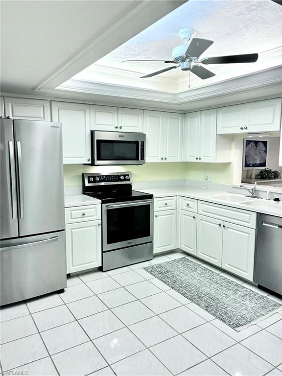 Kitchen with stainless steel appliances, light countertops, a ceiling fan, and light tile patterned floors