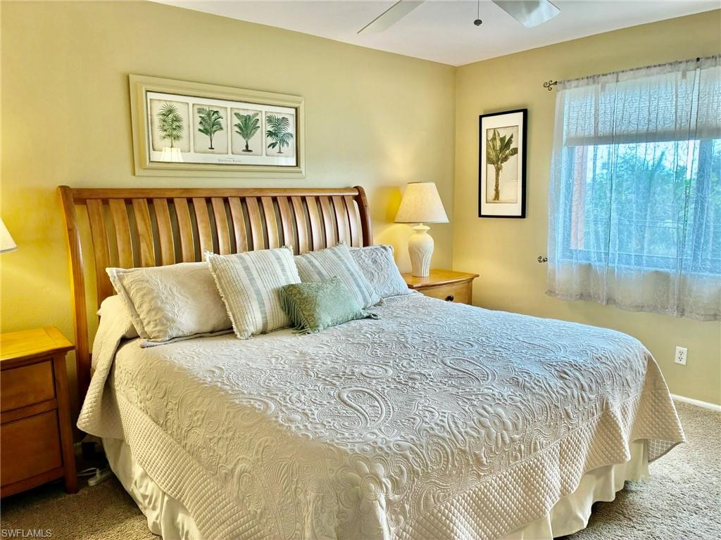 Carpeted bedroom with a ceiling fan and baseboards