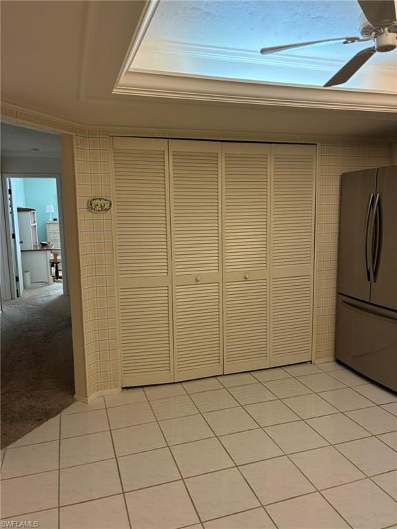 Unfurnished dining area with light tile patterned floors, ceiling fan, and light colored carpet
