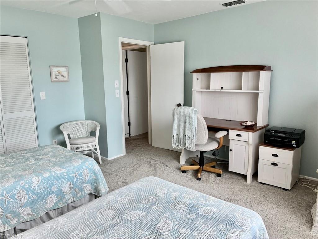 Bedroom featuring light colored carpet, an office area, and a closet