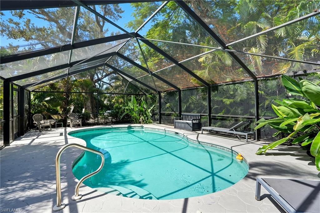 Swimming pool featuring glass enclosure, a sunroom, and a patio - Virtually Edited Image