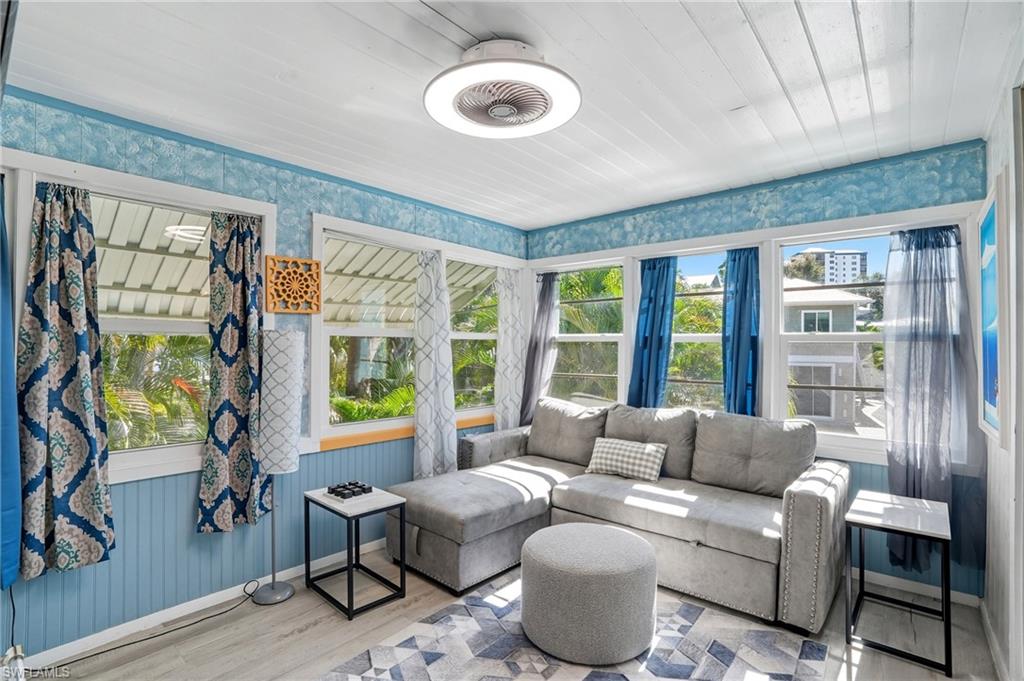 Sunroom / solarium featuring wood finished floors, wallpapered walls, and wood ceiling - Virtually Edited Image