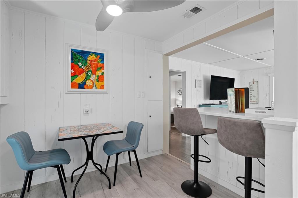 Dining area featuring light wood-style flooring, ceiling fan, and wood walls - Virtually Edited Image