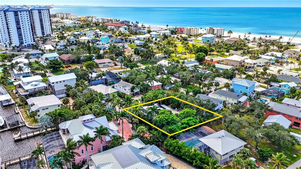 Aerial view of residential area featuring a large body of water and property parcel outlined - Virtually Edited Image