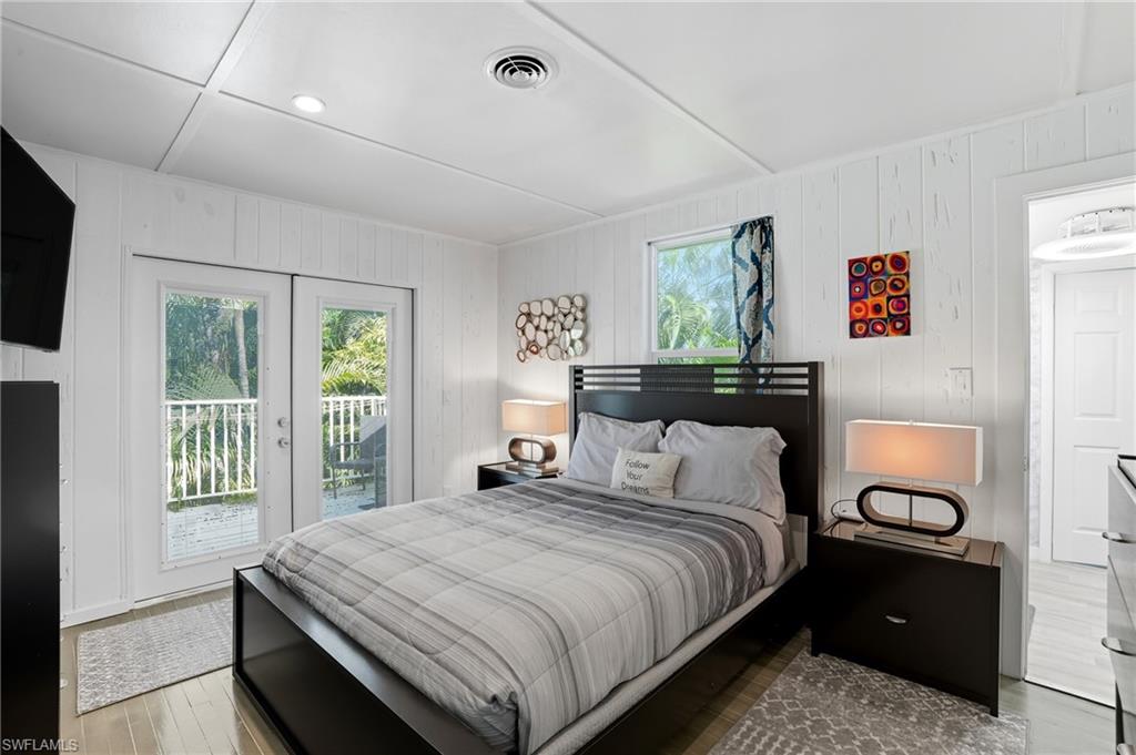 Bedroom with access to exterior, wooden walls, wood finished floors, and recessed lighting - Virtually Edited Image