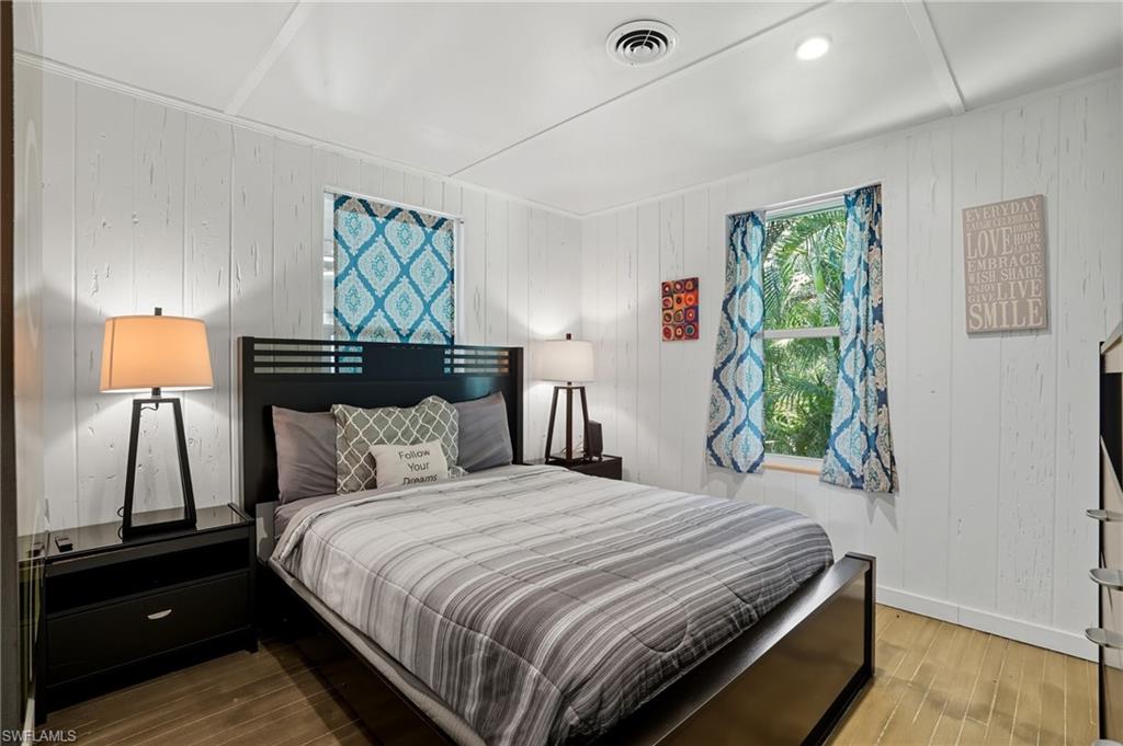 Bedroom featuring wood walls and wood finished floors - Virtually Edited Image