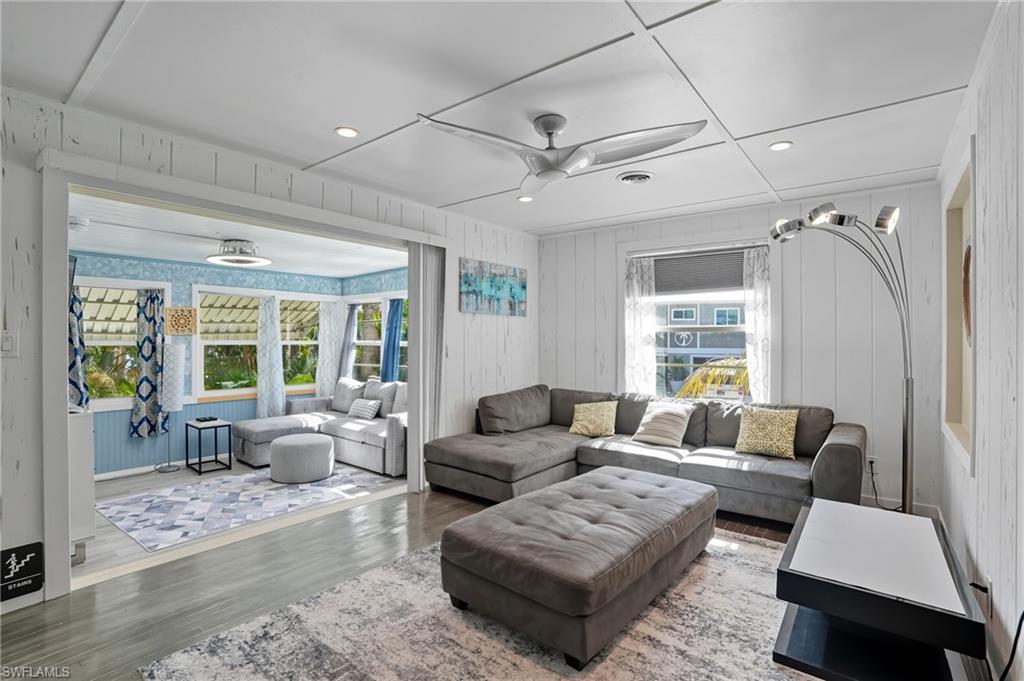 Living area with recessed lighting, wood finished floors, ceiling fan, and wood walls - Virtually Edited Image