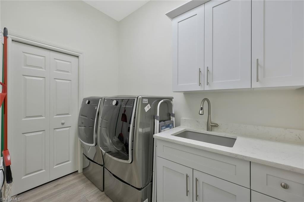 Washroom featuring washer and dryer, cabinet space, and light wood-style floors