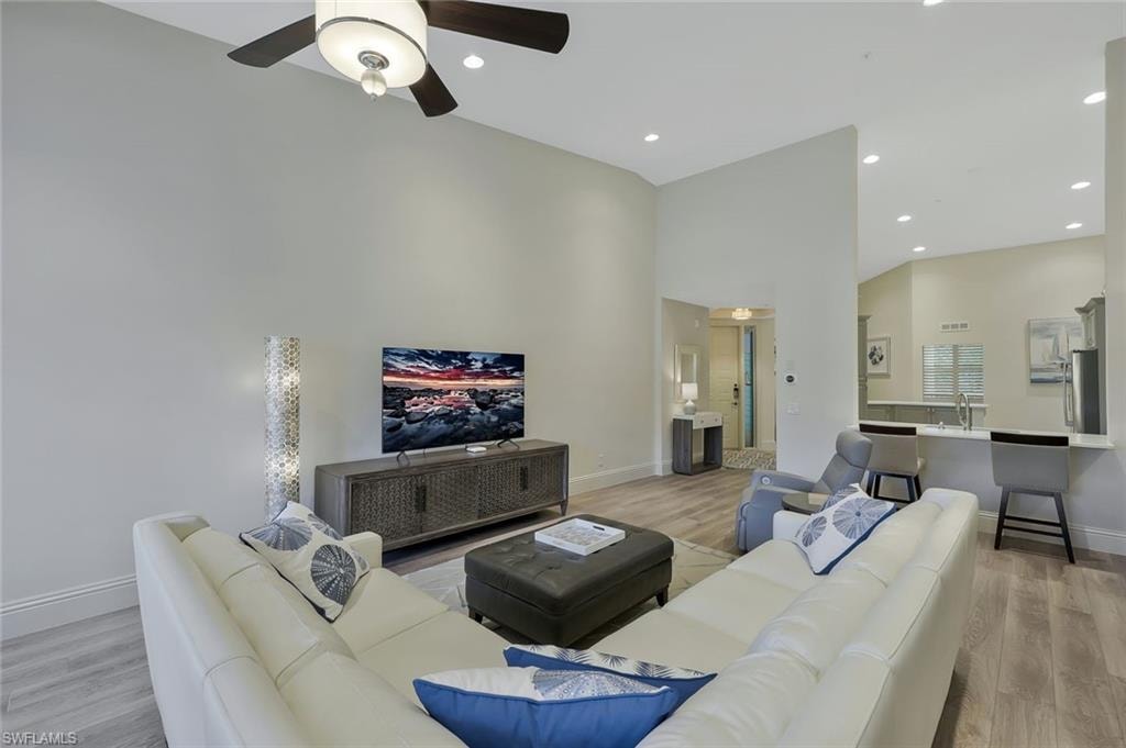Living room with light wood-style floors, recessed lighting, a towering ceiling, and a ceiling fan