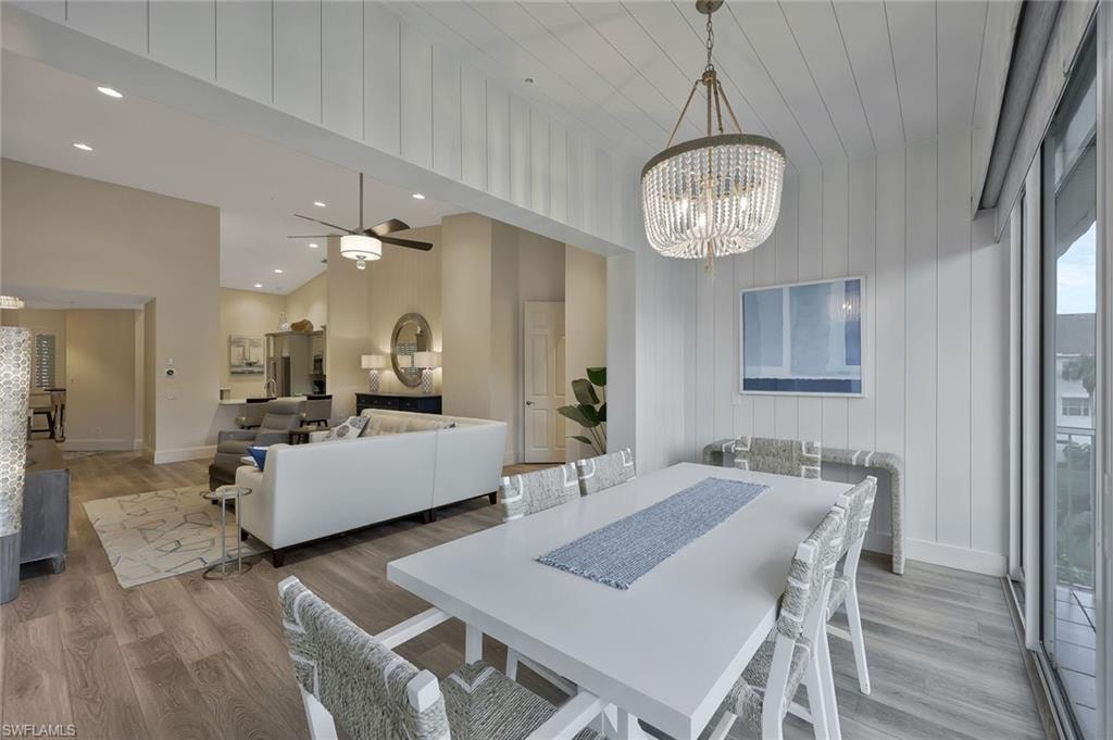 Dining room with ceiling fan, a chandelier, light wood-style flooring, a high ceiling, and recessed lighting