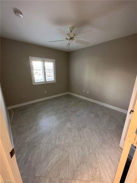 Empty room featuring a smoke detector and a ceiling fan