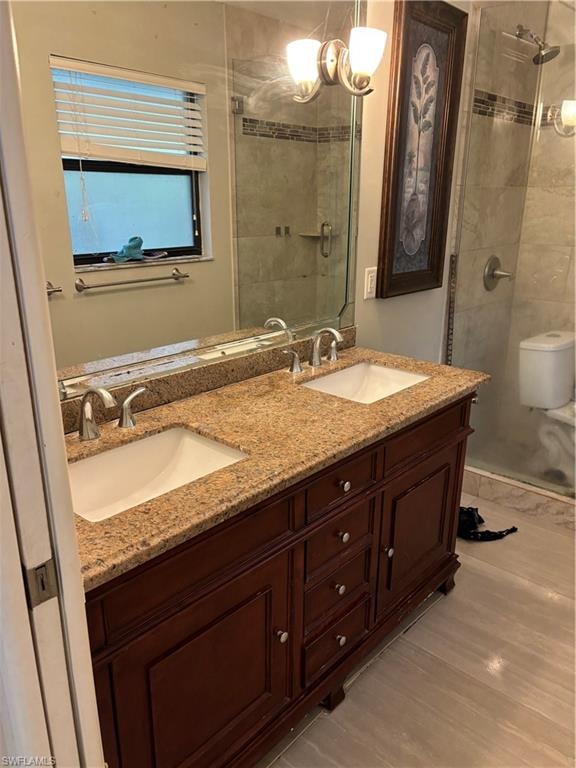 Full bath with double vanity, a shower stall, and light wood-style flooring